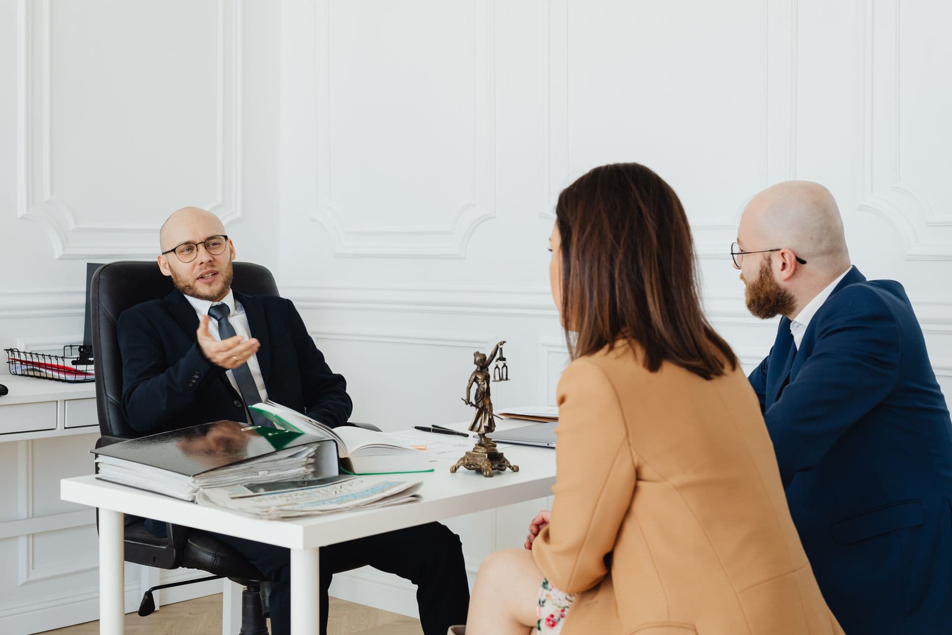 Un couple et son avocat évoquent les étapes d'un divorce par consentement mutuel dans un cabinet.